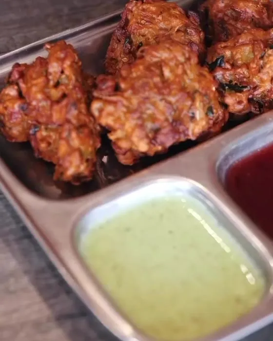 Pakora on a steel tray with green chutney